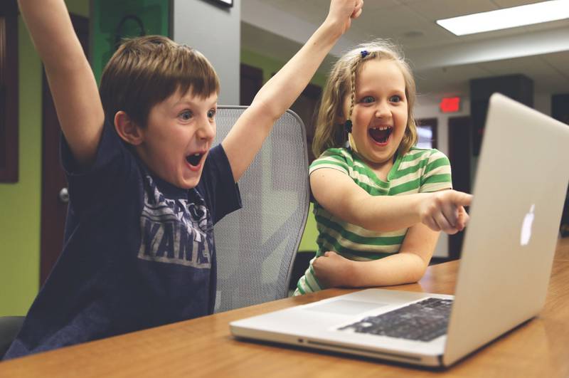 Dos niños muy felices frente a un computador