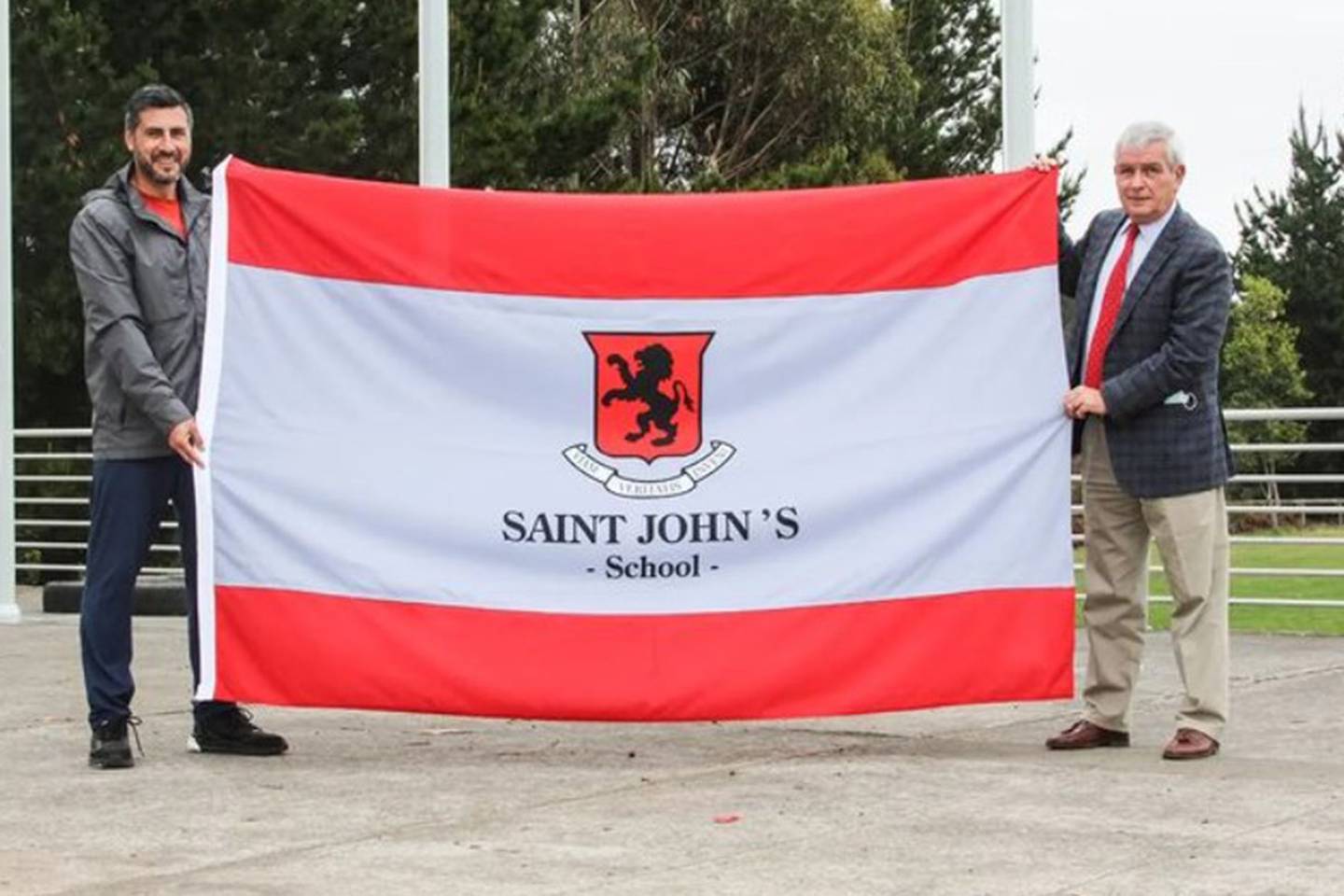 Autoridades del colegio privado de Concepción Saint John's School con una bandera de la institución.