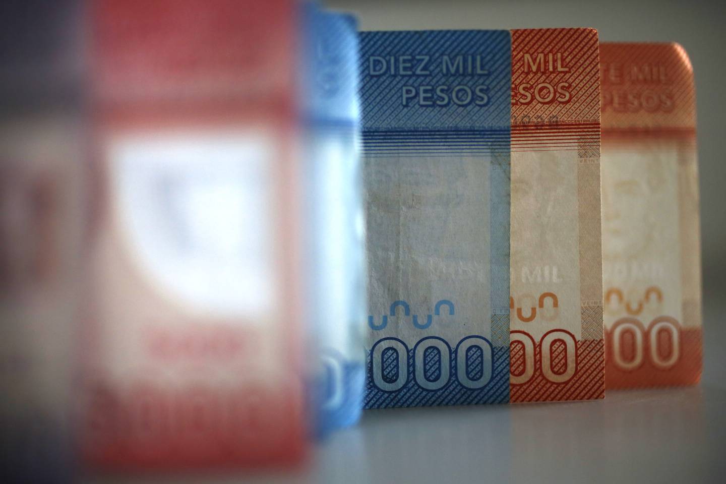 Billetes chilenos de distintos montos parados sobre una superficie plana en una fila.