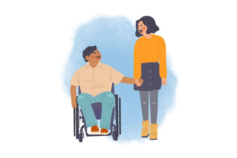 Persona con discapacidad en una silla de ruedas tomando de la mano a otra persona parada junto a él mientras ambos sonríen.