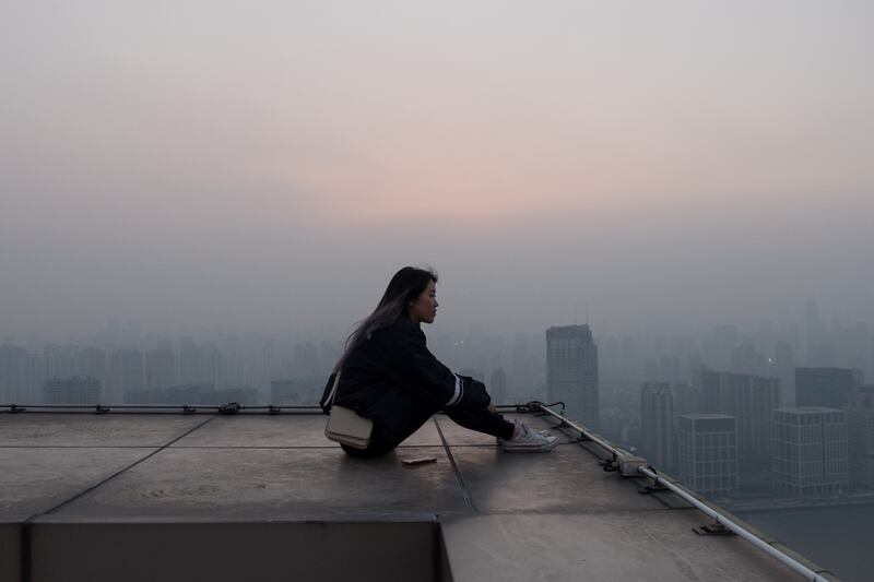 Mujer sentada en la azotea, mirando el horizonte.
