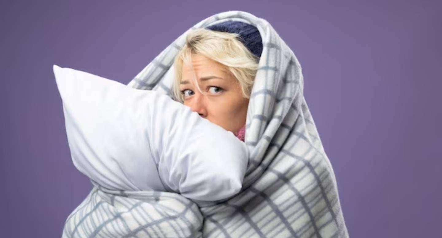 Mujer arropada con ropa de cama por el frío