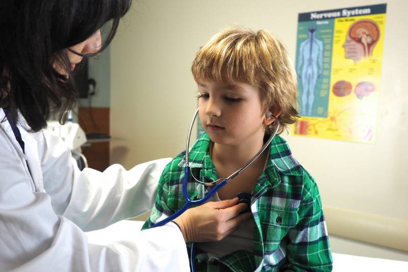 Doctora examinando a un niño sobre una camilla médica.