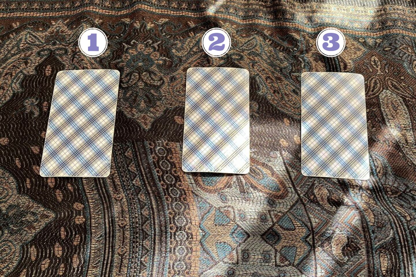 tres cartas del tarot al revés encima de una tela.