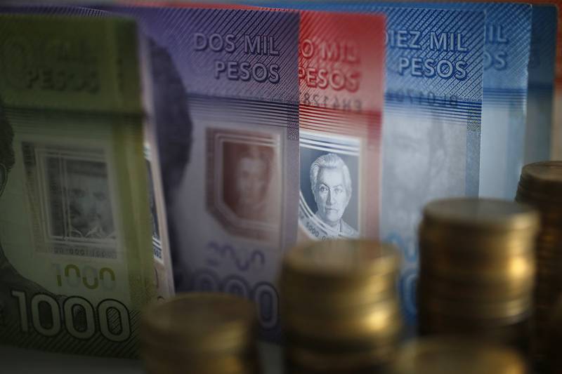 Billetes chilenos de $1000, $2000, $5000 y $10000 parados uno junto a otro y frente a ellos monedas chilenas de distintos valores.