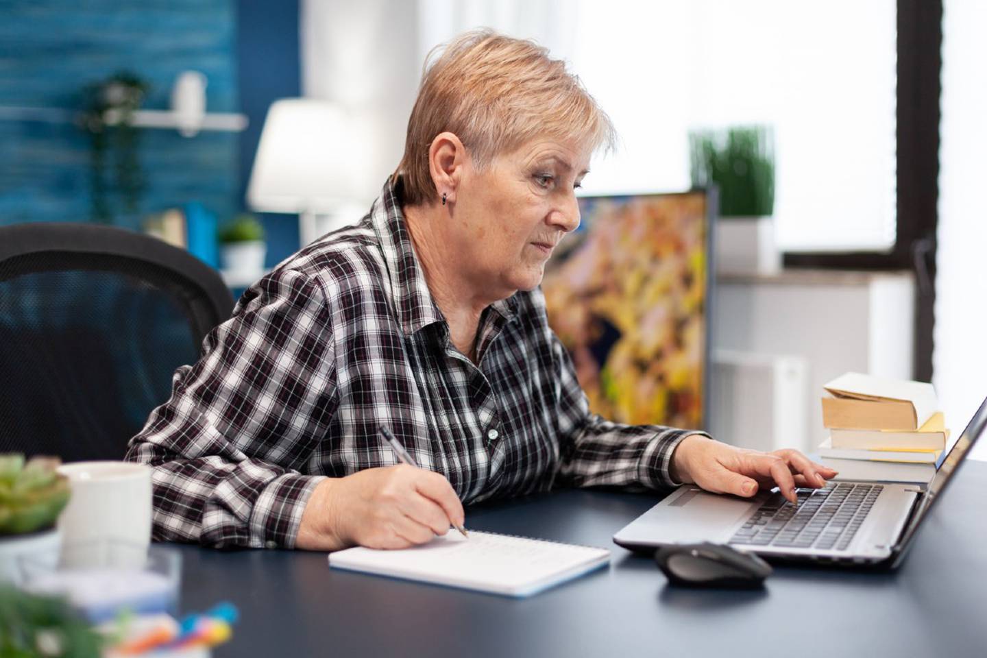 Mujer adulta mayor trabajando delante de un computador.