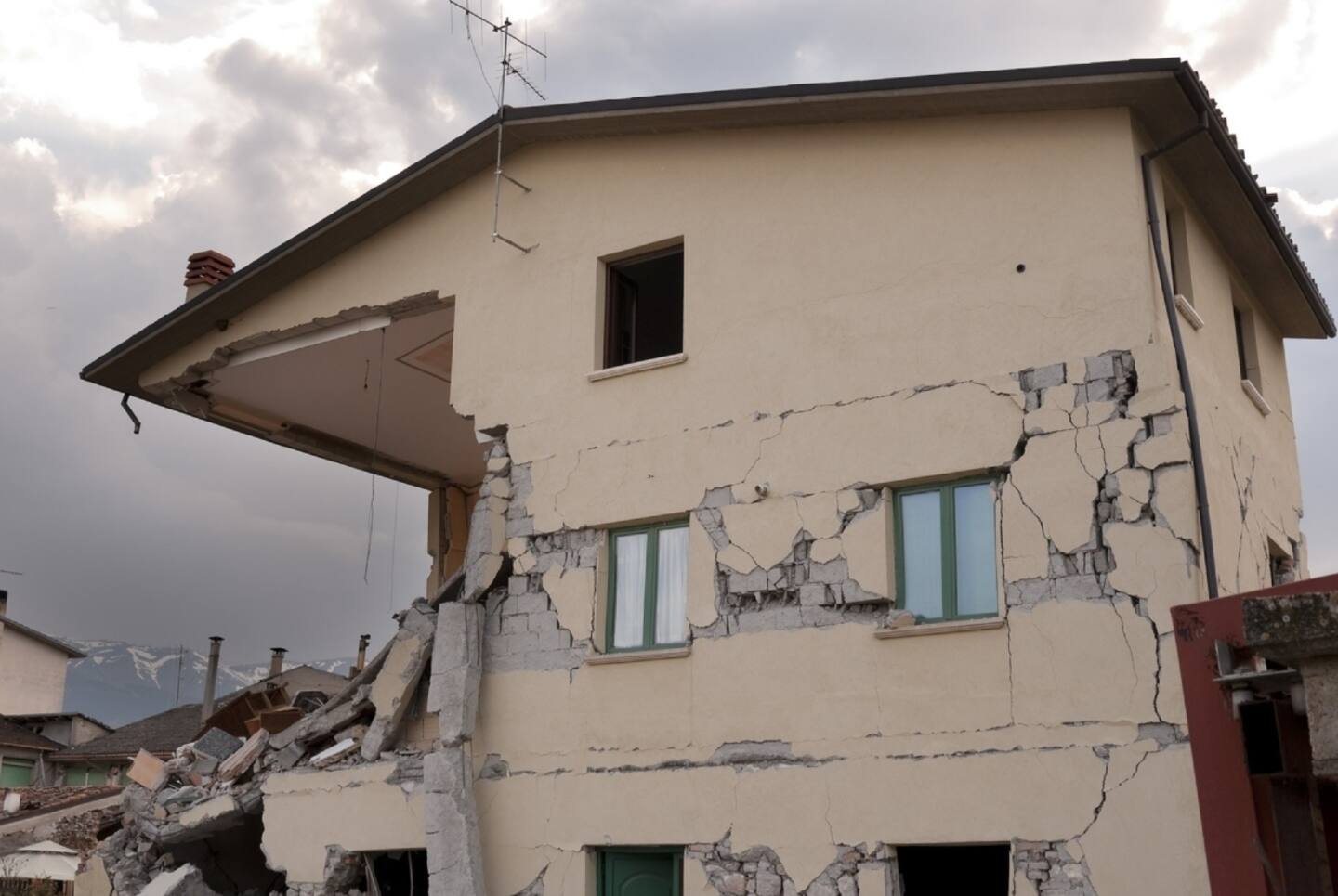 Una casa medio derrumbada por los efectos de un terremoto. Al lado, los restos del derrumbe.