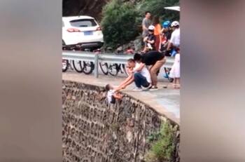Un peligro: Padres chinos cuelgan a su hijo para tomarle una foto en mirador
