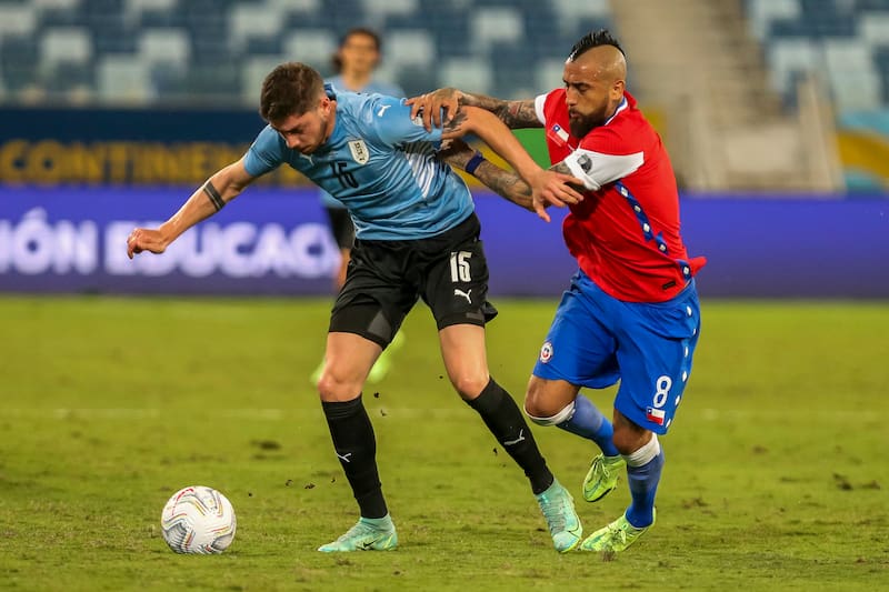 El jugador de Chile Arturo Vidal disputa el balón contra Federico Valverde de Uruguay
