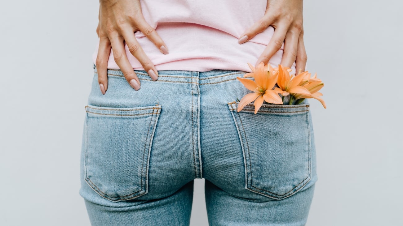 Glúteos femeninos vestidos con jeans y flores en el bolsillo trasero