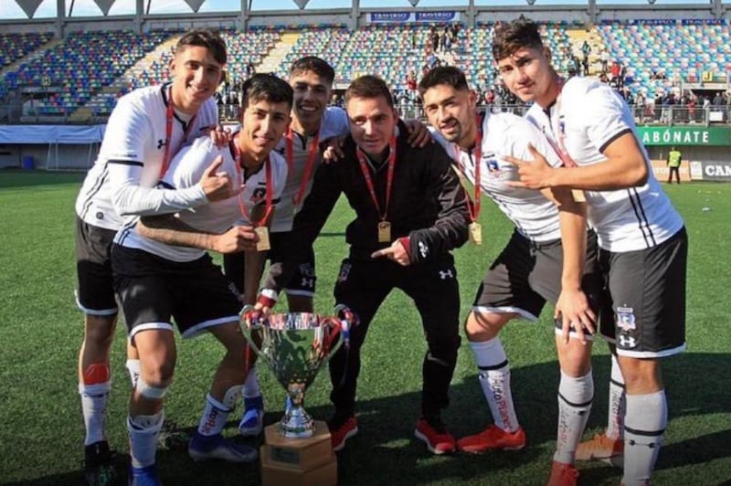 Los futbolistas Matías Ferrari, Bryan Soto, Pedro Navarro y Ethan Espinoza, entre otros, fotografiándose con la copa de campeón en la Sub 21 de Colo Colo en el año 2019.