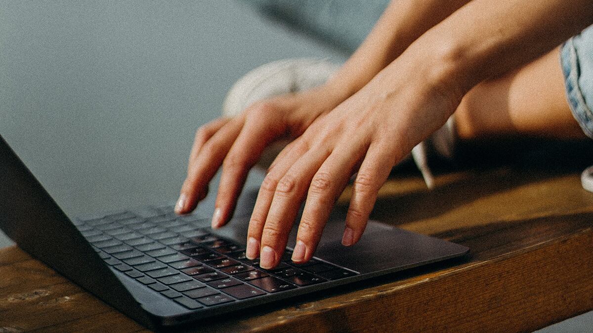 Mujer teclea en su computadora.