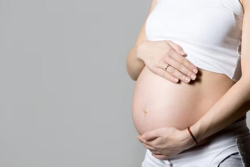 Mujer embarazada sostiene su vientre en avanzada gestación.