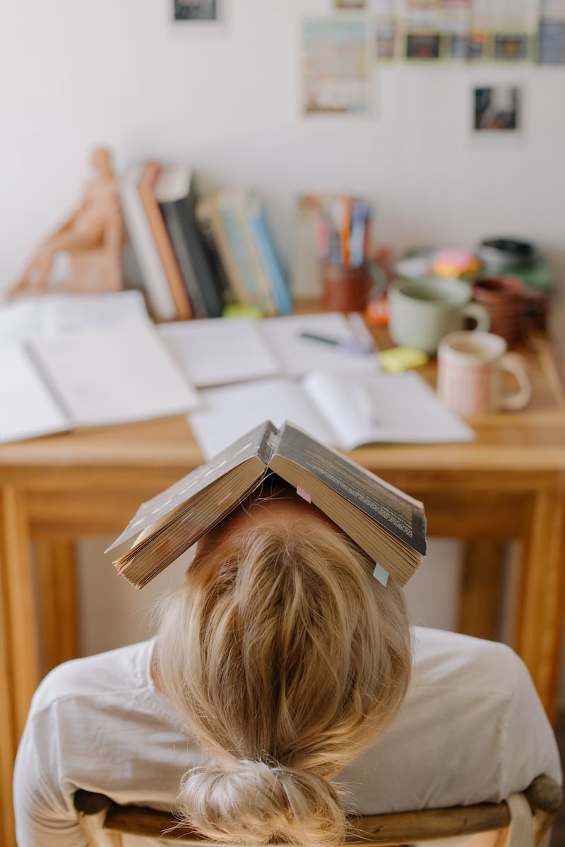 Estudiante universitaria descansa con un libro sobre la cara.
