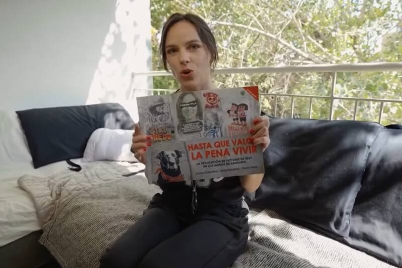 mostrando el libro de su autoría sobre el Estallido Social. Créditos: La Divina Comida.