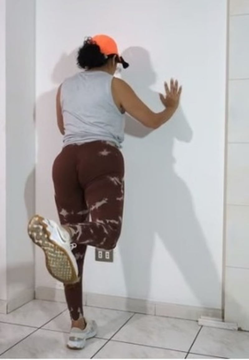 Mujer haciendo levantando las piernas, apoyada en una muralla