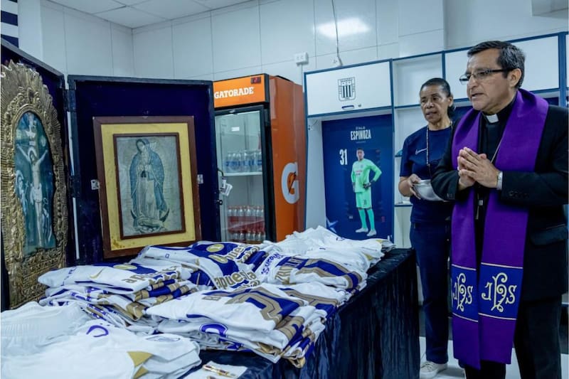 Un sacerdote bendice las camisetas moradas que utilizará el club Íntimo en octubre, en señal de devoción por el Señor de los Milagros.