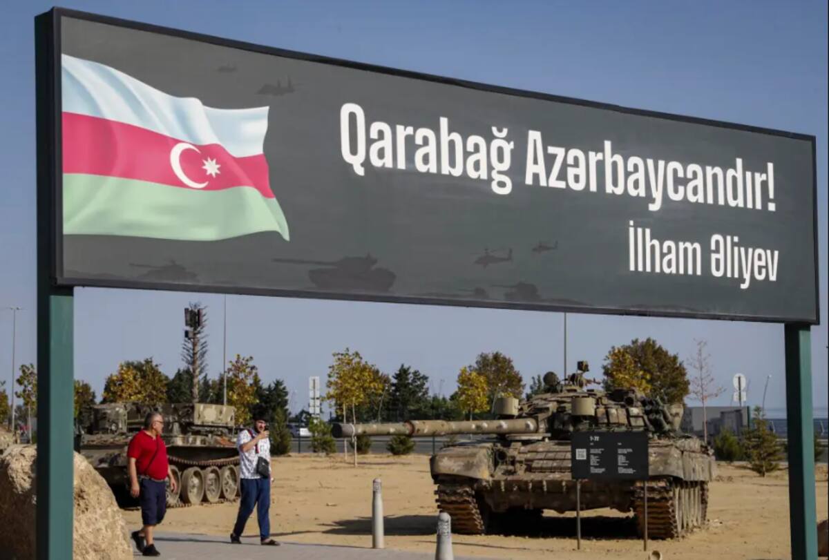 Personas pasean junto a un cartel que dice "Karabaj es Azerbaiyán"