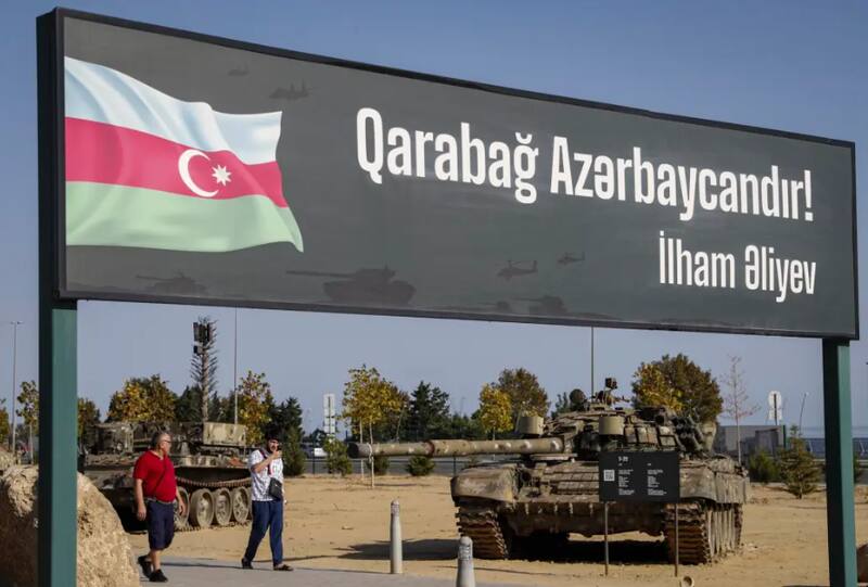 Personas pasean junto a un cartel que dice "Karabaj es Azerbaiyán"