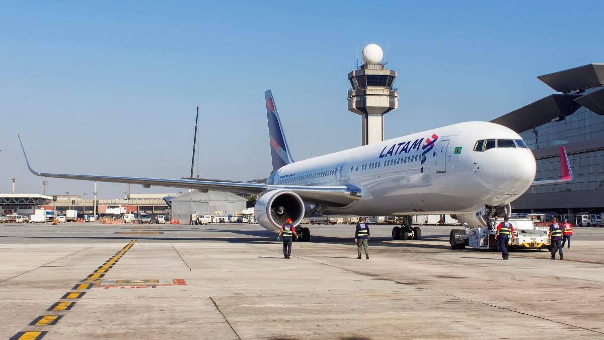 Boeing 767 of Latam Airlines push back with air traffic controller tower in background at Guarulhos International Airport in Sao Paulo Brazil