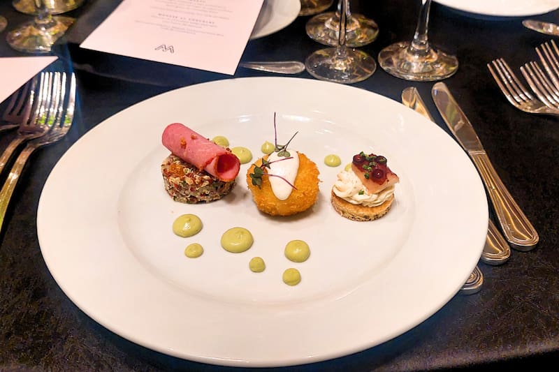 El appetizer consta de tres bocados que incluyen pulpo ahumado, queso crema y eneldo, arancini de risotto en panko con carne de jaiba y pastrami con miel, quinua andina y tártara de ají verde. Créditos: En La Hora.