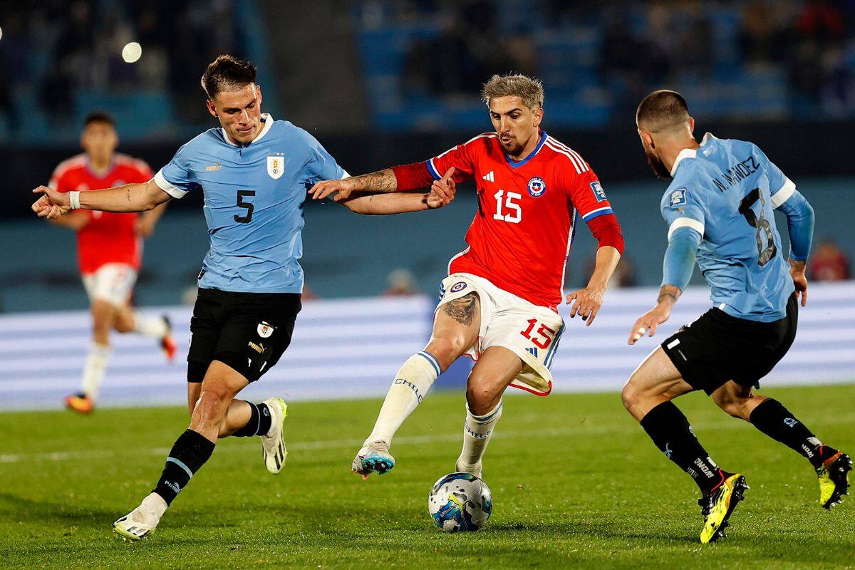 Diego Valdés intenta pasar entre los uruguayos Manuel Ugarte (5) y Nahitan Nández, en el partido del viernes en Montevideo por las Eliminatorias Sudamericanas al Mundial 2026.